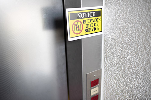 A photo of an elevator with a yellow out of service sign on it.