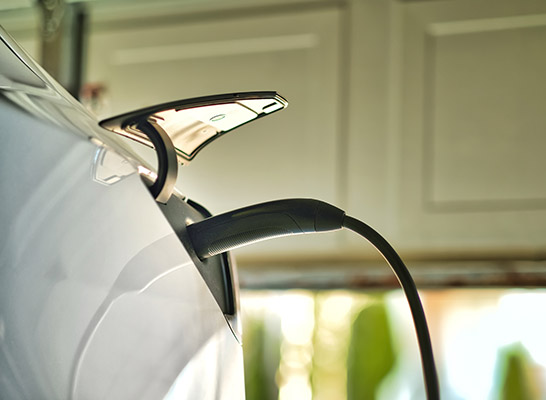 An image of a white car, charging on a home EV charger inside a garage