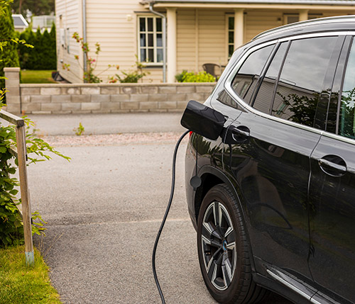 photo of a black car charging in their driveway.