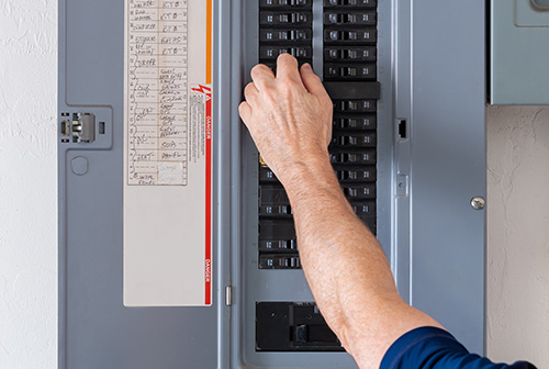 A photo of a person flipping a switch on a circuit breaker