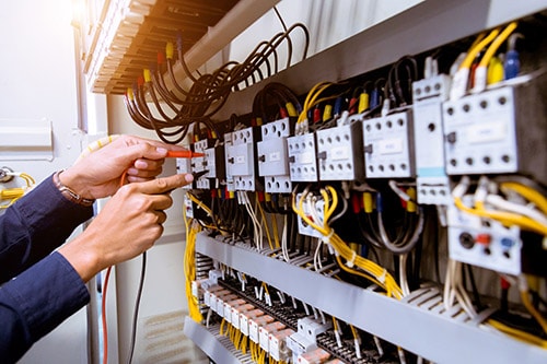 Electrician measures current in electrical control panel
