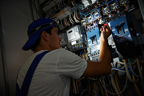 An electrician works in the dark, fixing an electrical issue. 