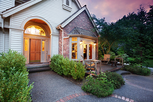 An image of a house with white siding and a brick wall lit up through the windows.